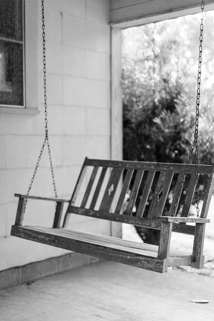 Wooden porch swing in black and white.